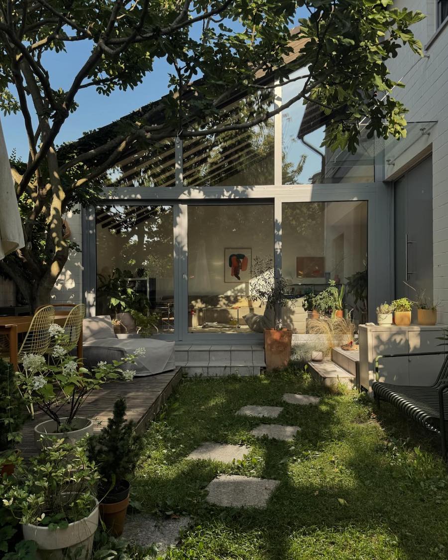 a shaded backyard patio with furniture and houseplants