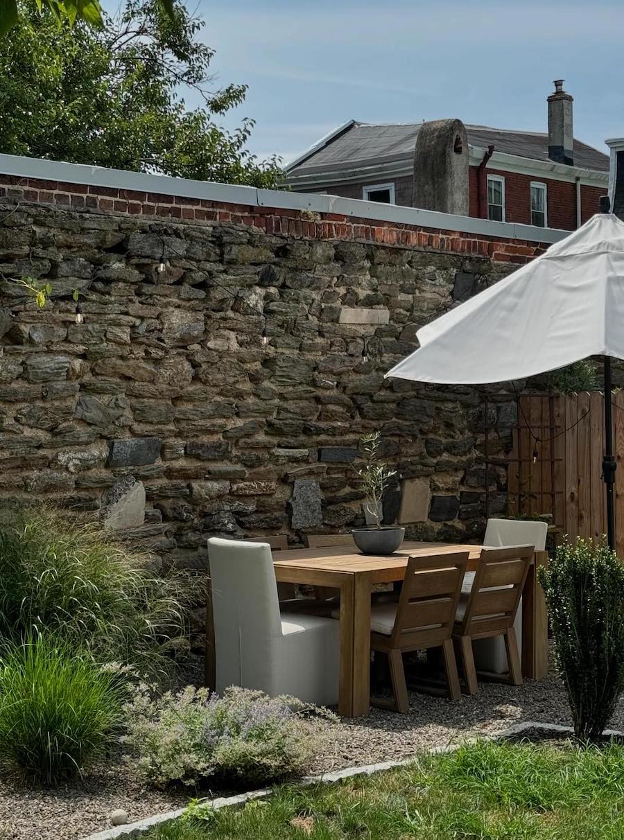 a small dining table and umbrella in a backyard