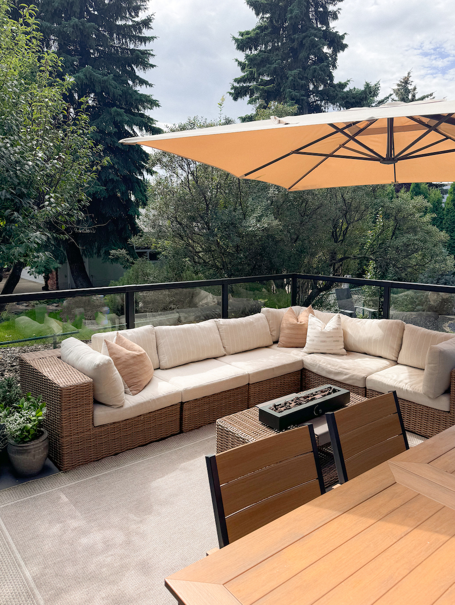 a backyard patio with a large couch, a dining table, and an umbrella