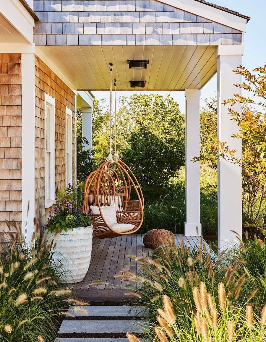 a front porch with boho furniture and floral arrangements