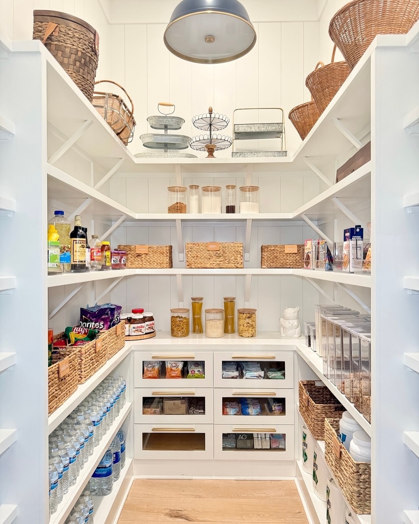 a large pantry with built in shelves and baskets and bins for organization