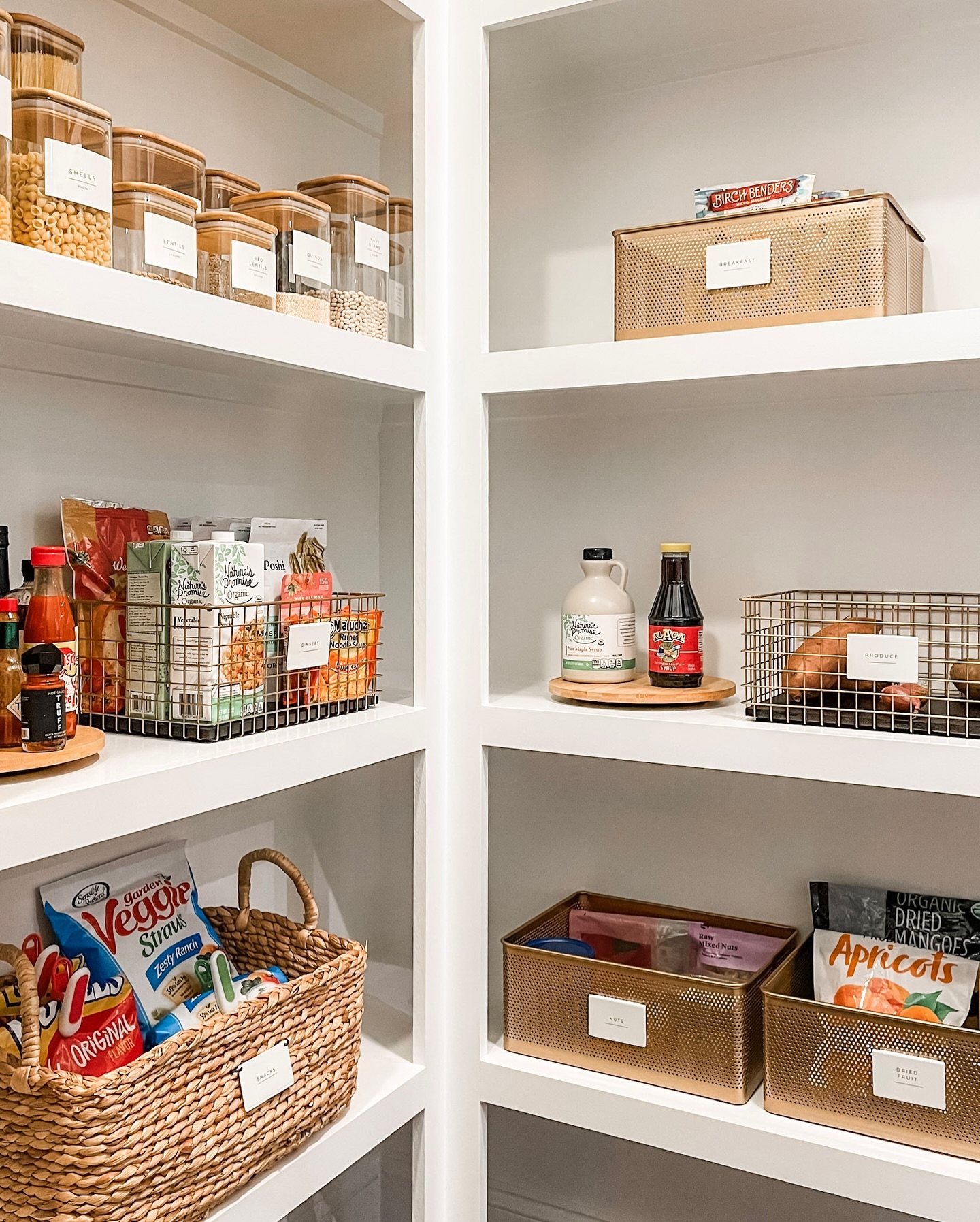 a pantry with built in shelving, glass canisters, and wire and wicker baskets